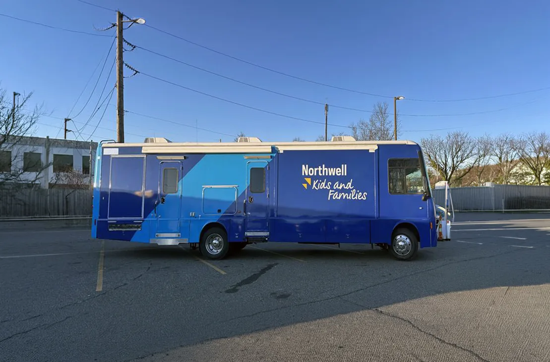 The Northwell Kids and Families RV wrapped in two tones of blue, parked in an empty lot.