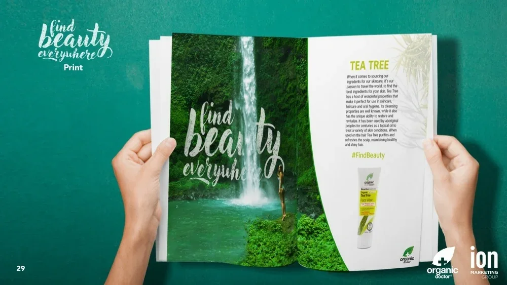 Presentation slide showing hands holding open a magazine spread: waterfall image with the lettering on the left, a Tea Tree ingredient story and face wash product on the right.