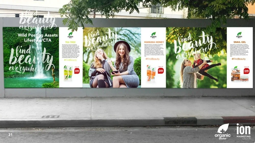 Presentation slide showing a street-level wall of wheatpasted posters alternating lifestyle images with Tea Tree, Manuka Honey and Snail Gel ingredient panels, each carrying a CVS exclusivity flag.
