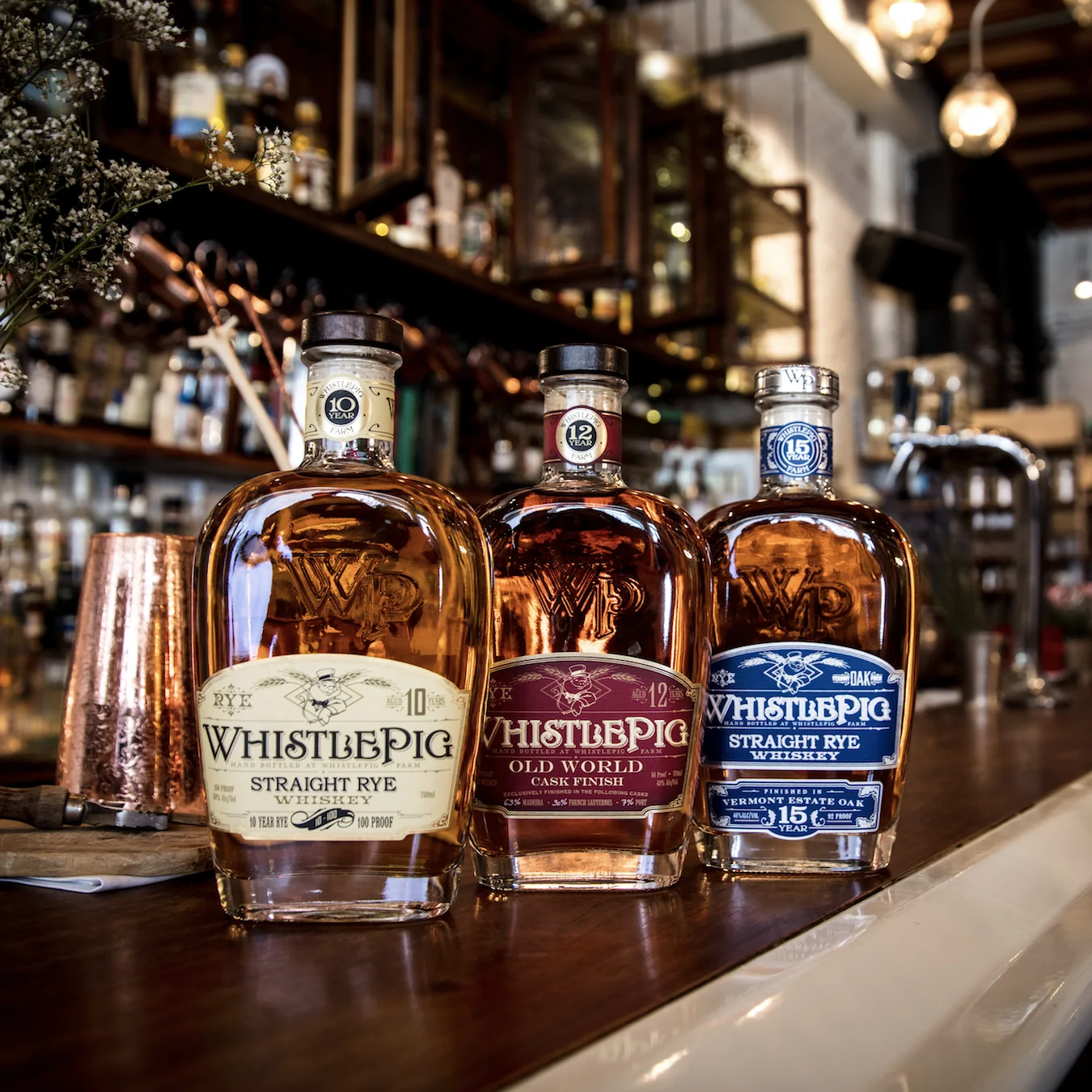 Three WhistlePig bottles lined up along a bar top.